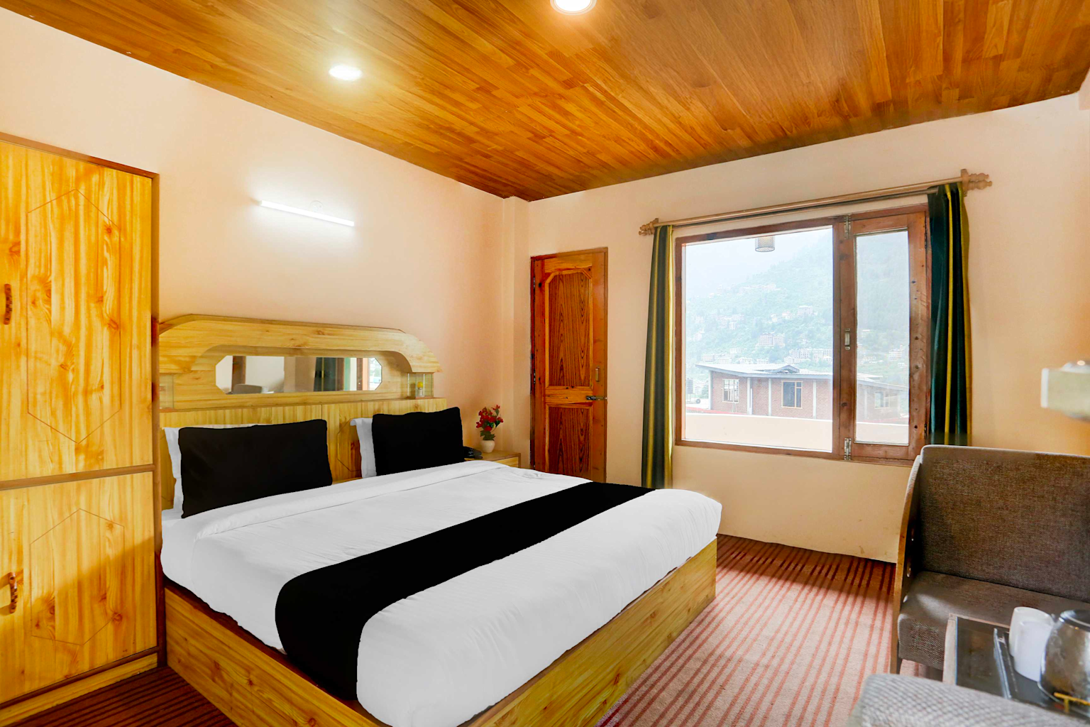 Cozy budget hotel room in Manali with wooden interior and a mountain view