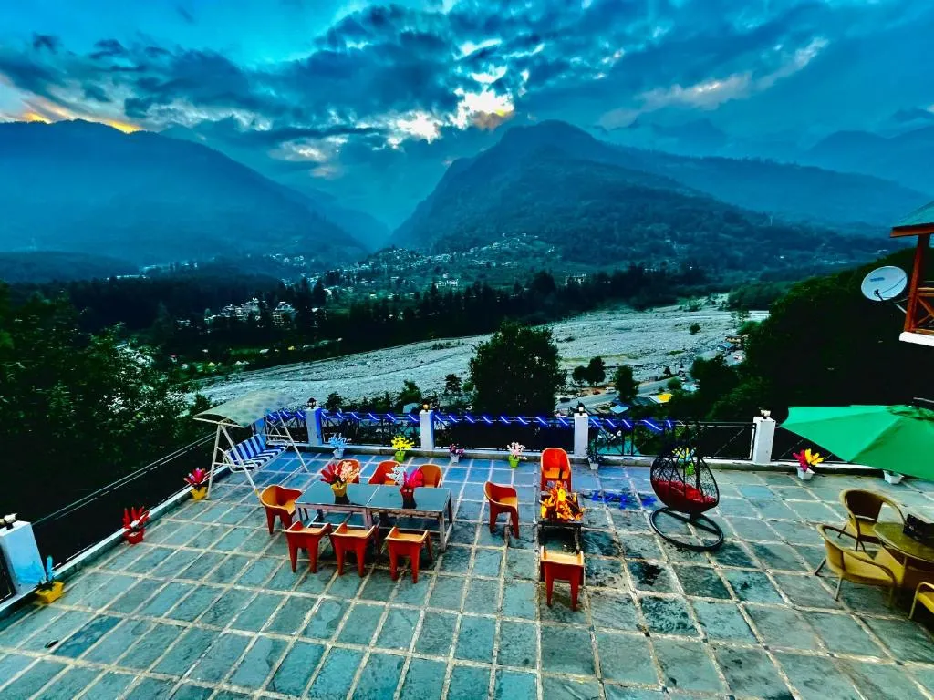 Outdoor terrace seating with fire pit overlooking a scenic mountain valley in Himachal Pradesh
