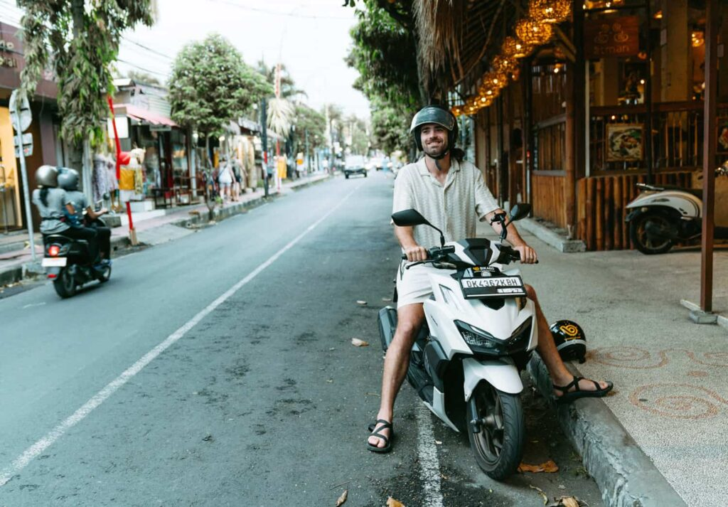 A traveler sitting on a rented scooter in Bali, illustrating a popular and affordable mode of transportation for budget travelers exploring the island