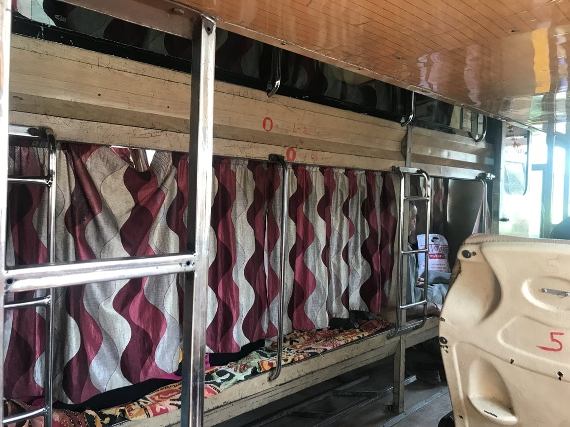 Interior of a sleeper bus or train coach in India showing budget-friendly sleeping berths with privacy curtains and ladders