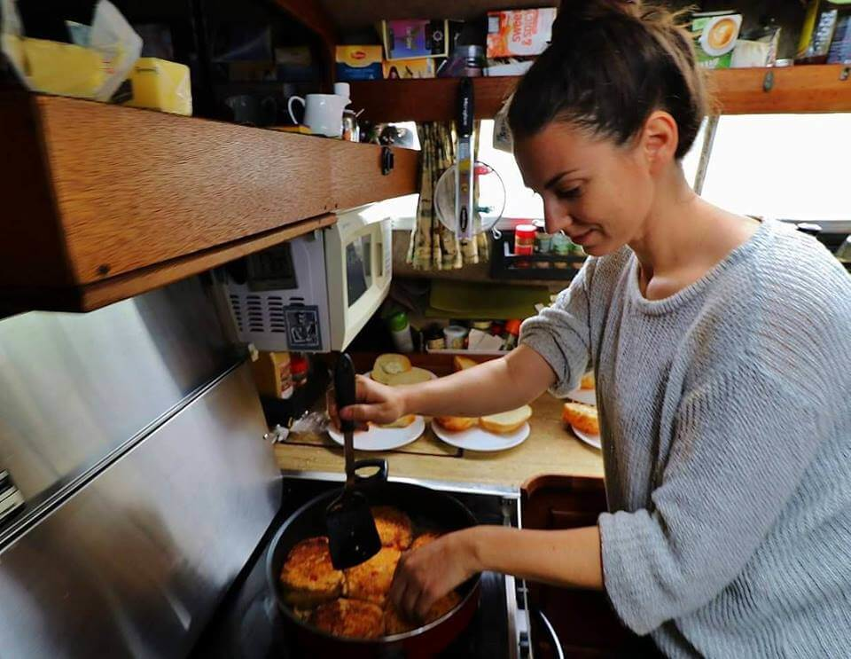 Traveler cooking budget-friendly meals in a hostel kitchen to save money on food while traveling