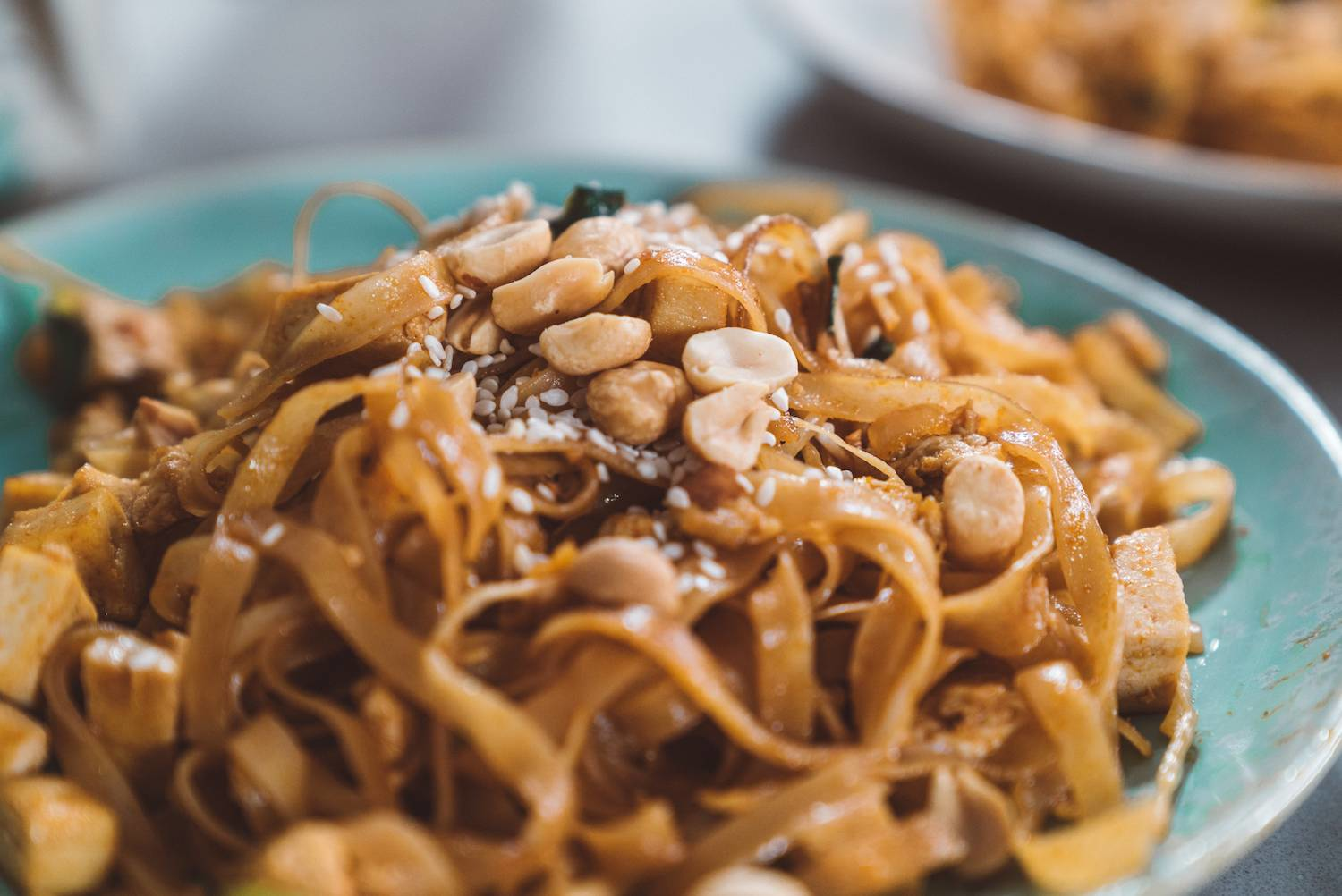 A close-up of authentic Pad Thai garnished with peanuts and sesame seeds, showcasing a popular and affordable Thai street food dish suitable for budget travelers