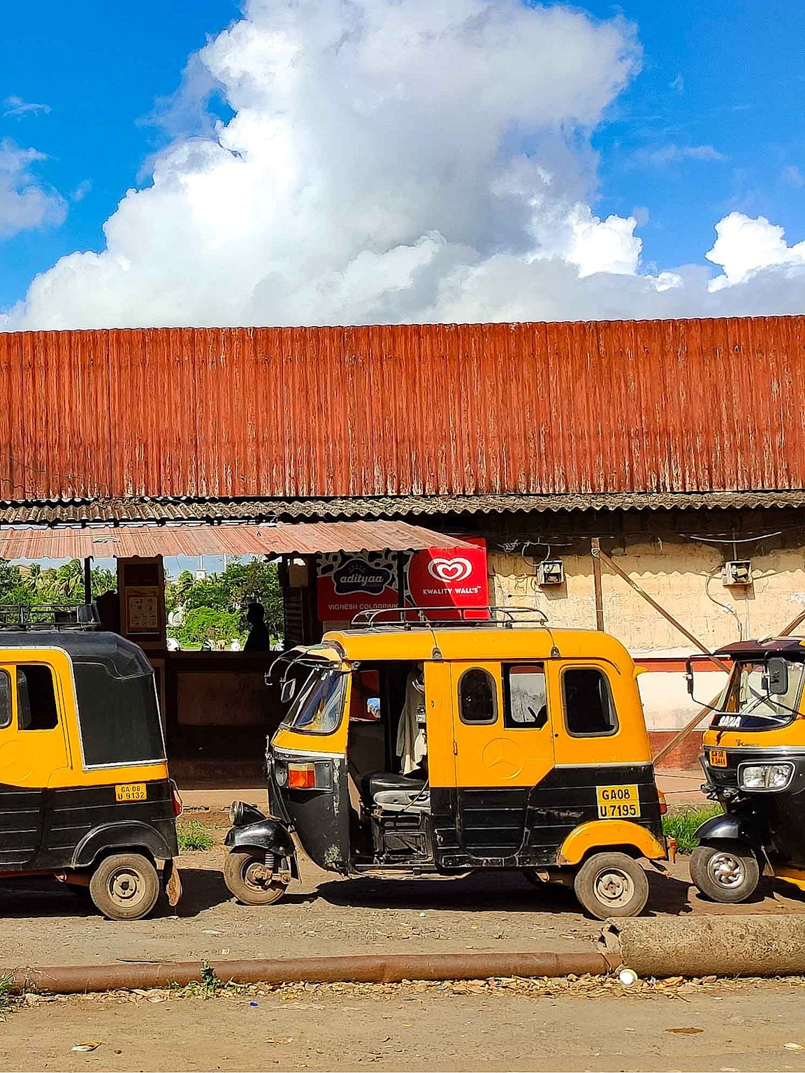 Traditional yellow-black auto rickshaws parked in Goa, a popular local transport mode for budget travelers