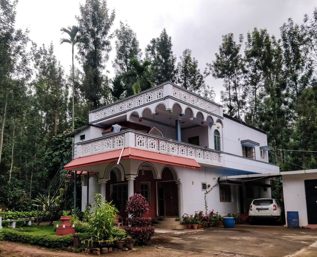 A charming two-story homestay nestled in greenery illustrating budget-friendly accommodation options in India