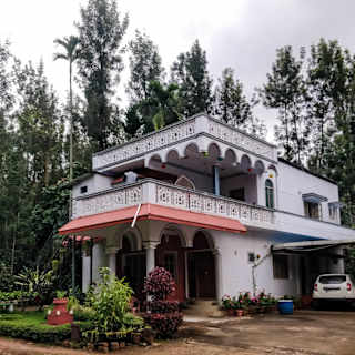A charming two-story homestay nestled in greenery illustrating budget-friendly accommodation options in India