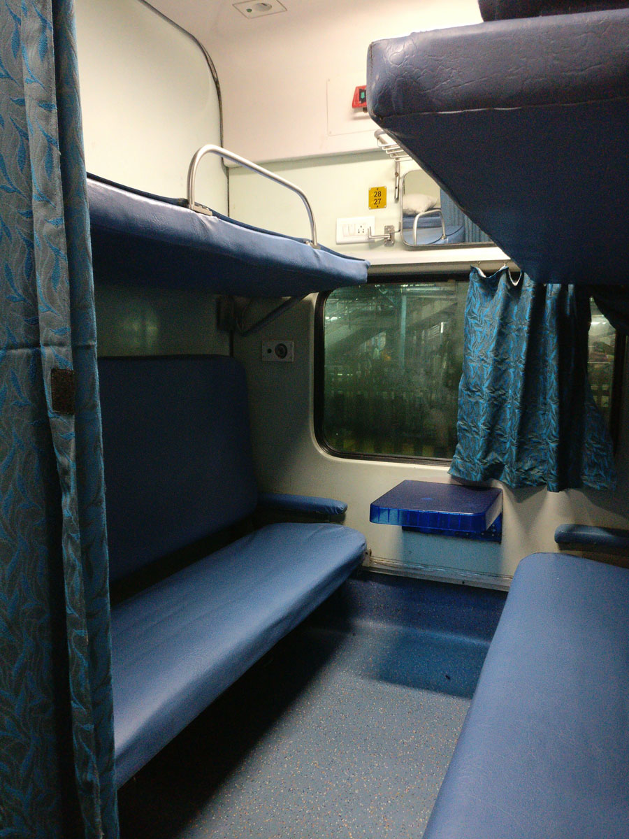Interior of an Indian train's AC sleeper coach showing seating and berths for budget-friendly long-distance travel