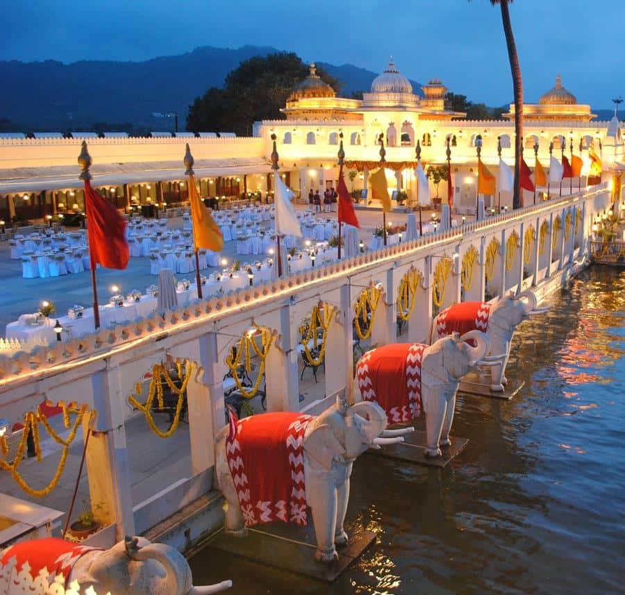 Illuminated Udaipur Lake Palace with decorated elephant statues along Lake Pichola at dusk, part of a cultural tour experience in Rajasthan