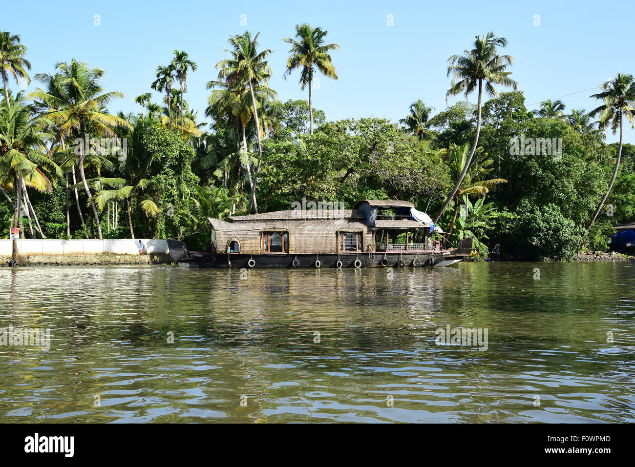 Traditional Kerala houseboat on scenic backwaters surrounded by lush coconut trees and tropical greenery