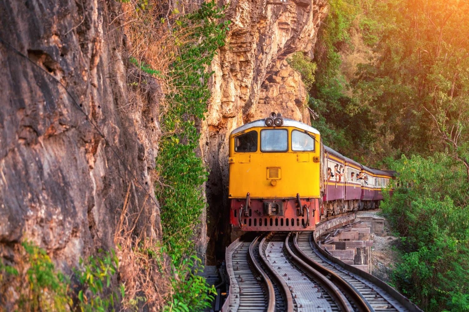 A scenic passenger train journey through rocky and forested terrain in India, showcasing an adventurous travel route