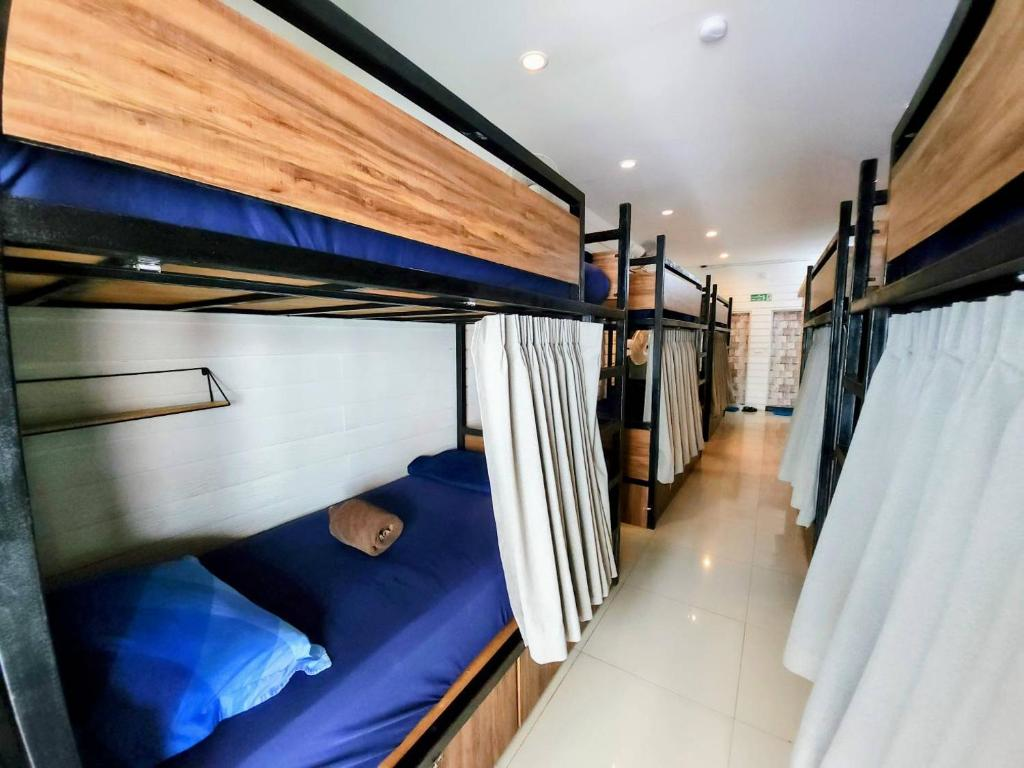 Interior view of a clean and budget-friendly backpacker hostel dormitory room in Bangkok, Thailand with bunk beds and privacy curtains