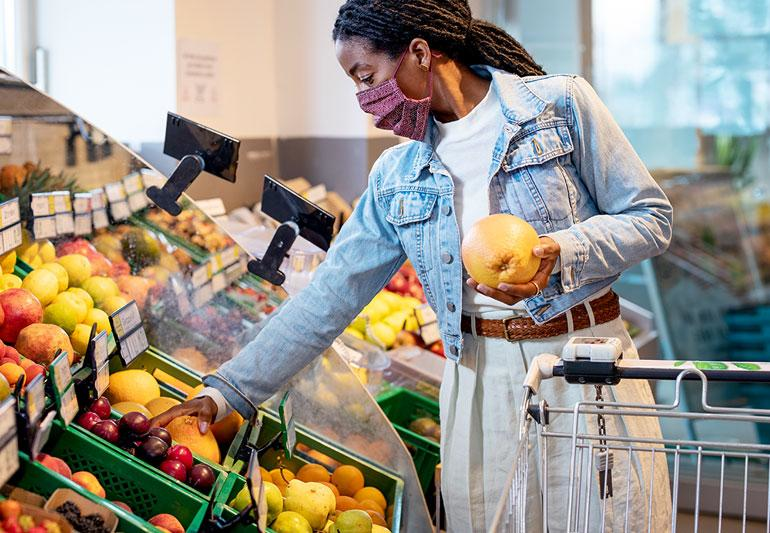 A person selecting fresh local fruits at a market to save money while traveling