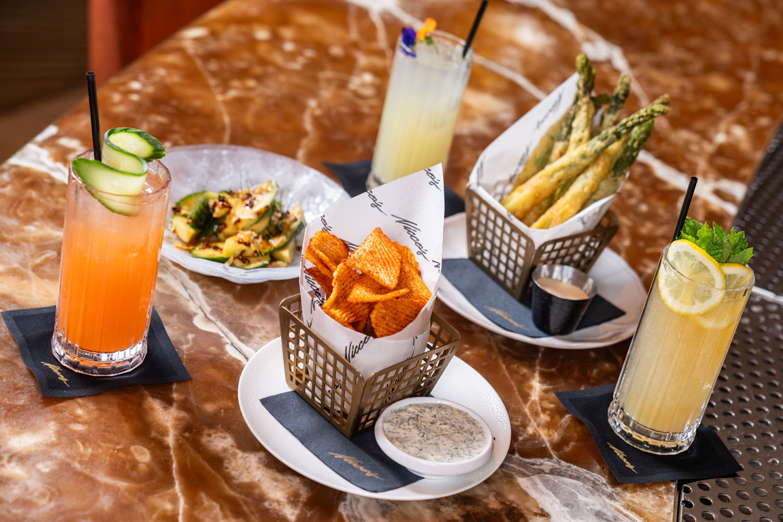 Assorted happy hour appetizers and colorful cocktails on a table, showcasing budget-friendly dining options